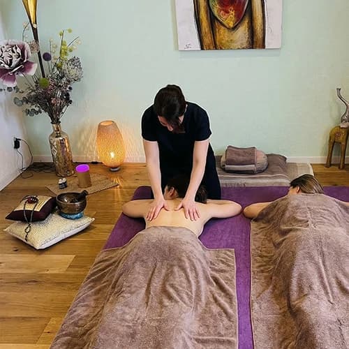Veronika Mutti massiert bei einer Paarmassage zwei nebeneinander liegende Personen