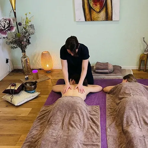 Veronika Mutti massiert bei einer Paarmassage zwei nebeneinander liegende Personen