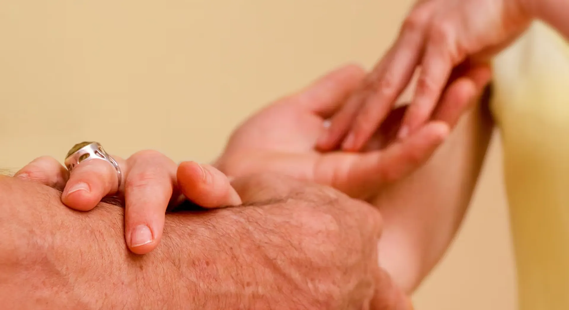 Zwei Hände, die sich sanft berühren, symbolisieren Verbindung und Fürsorge für Tantra Massage Kurs